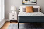 Hybrid mattress with white quilted top and dark gray sides, styled with pillows
