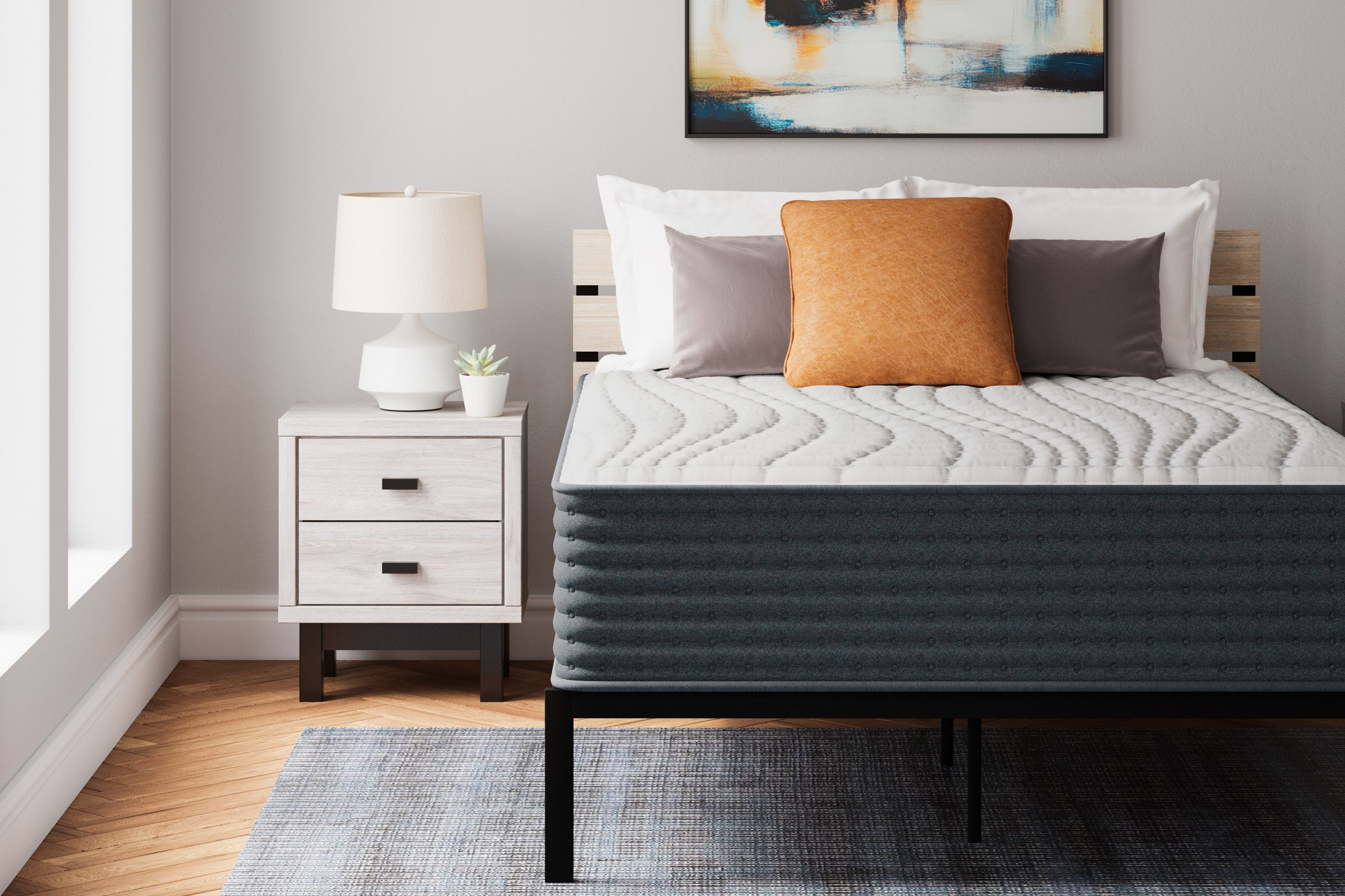 Hybrid mattress with white quilted top and dark gray sides, styled with pillows