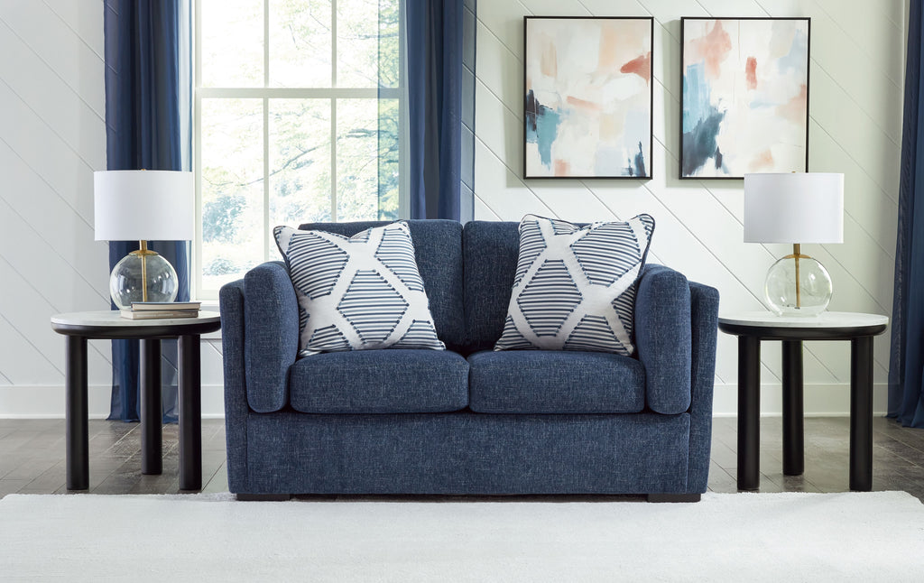 Blue loveseat sofa with two white-and-blue striped throw pillows