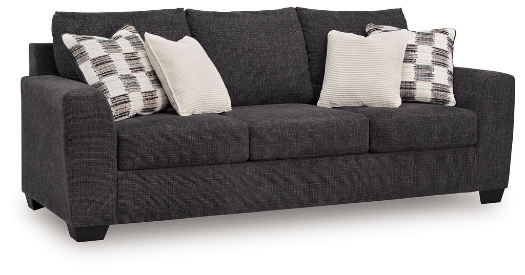 Sofa sleeper, dark gray upholstery with plaid and white throw pillows.