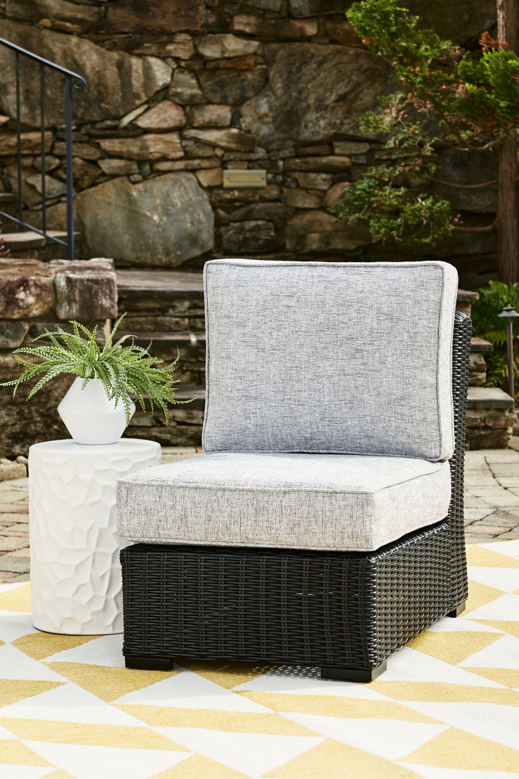 Light gray armless outdoor chair cushion on black woven wicker base