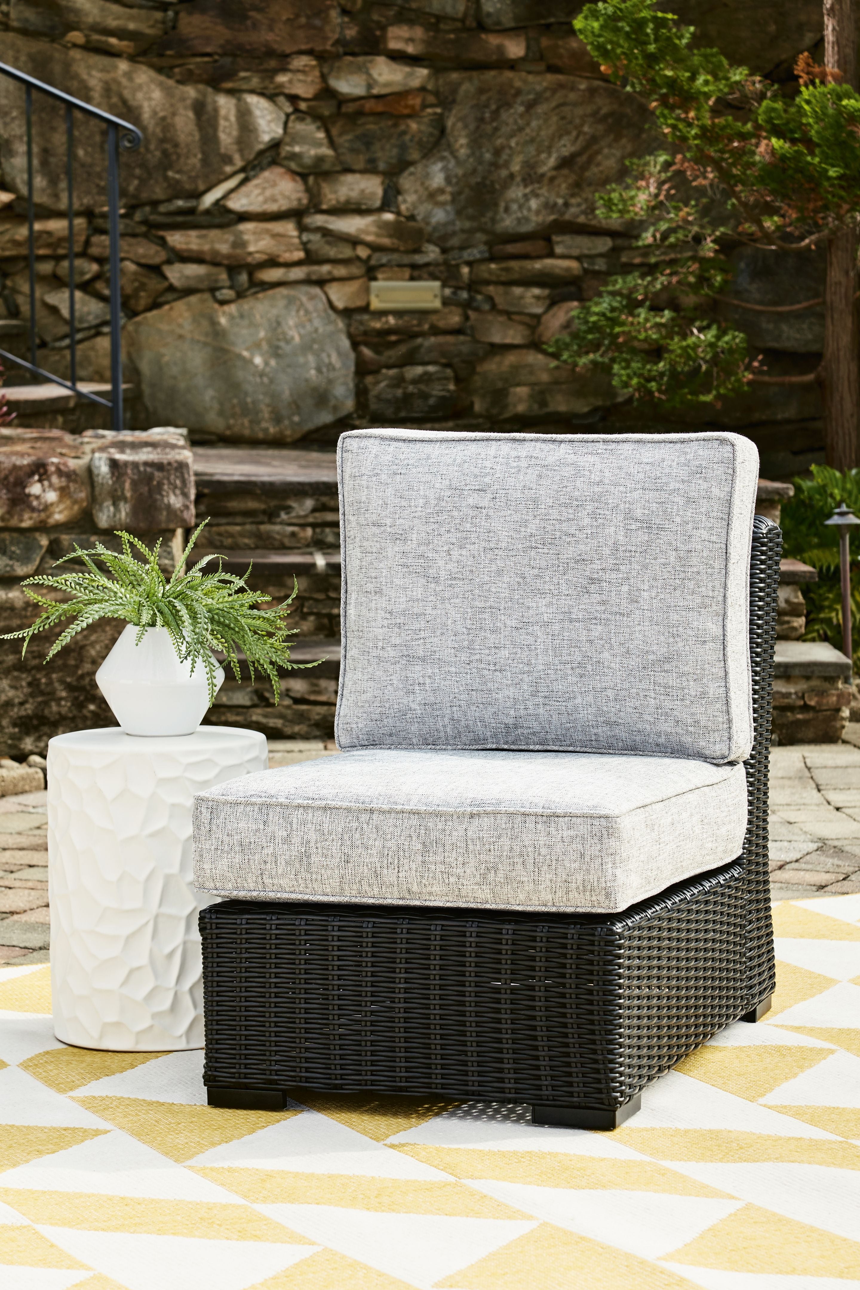 Light gray armless outdoor chair cushion on black woven wicker base
