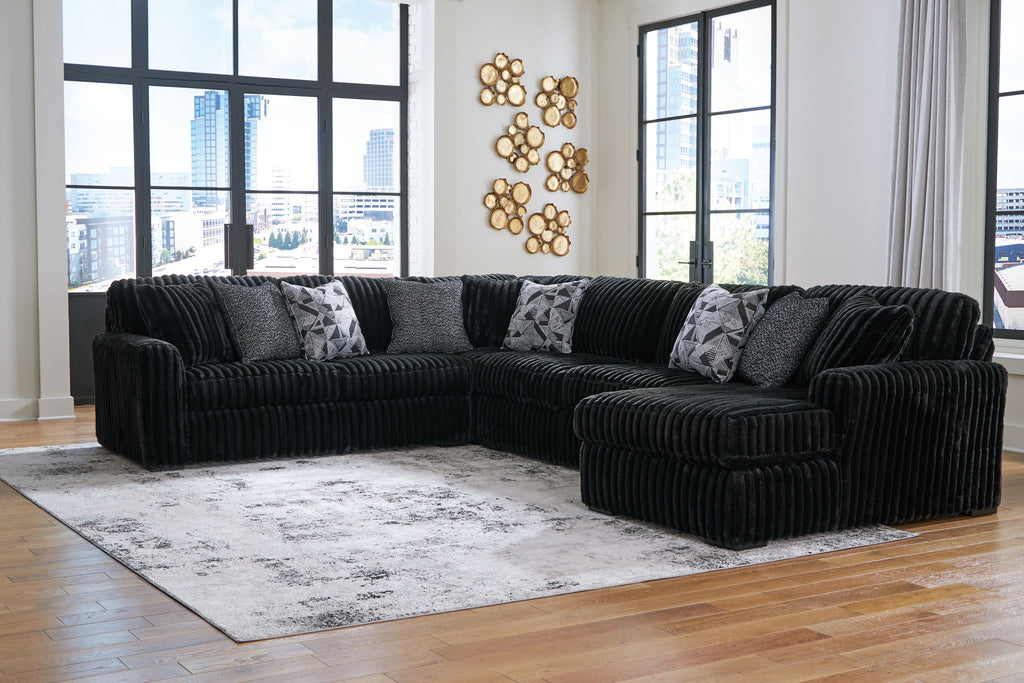 Black corded sectional sofa with chaise corner and gray patterned throw pillows