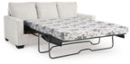 Beige sofa bed with pulled-out mattress and floral patterned cover