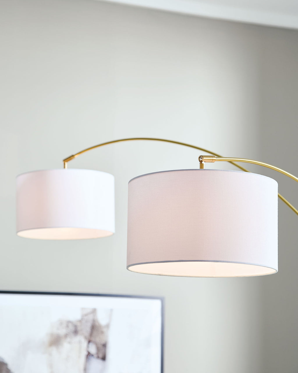 Gold arc floor lamp close-up with two white drum shades