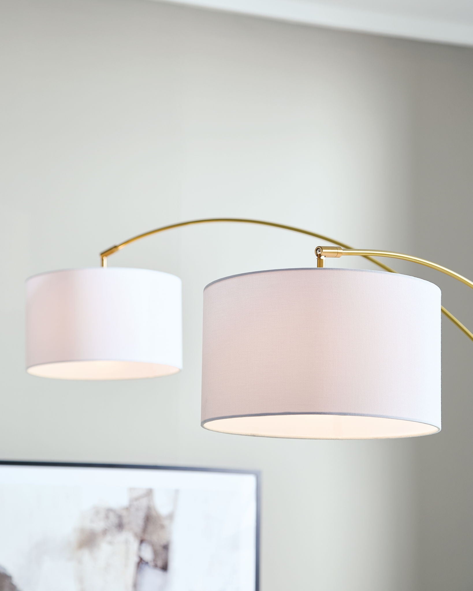 Gold arc floor lamp close-up with two white drum shades
