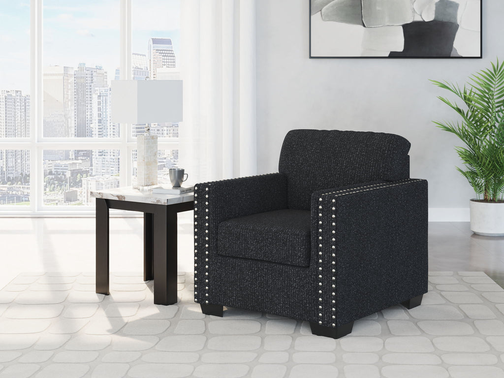 Dark charcoal upholstered armchair with padded back and silver nailhead trim.