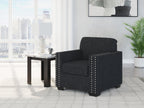 Dark charcoal upholstered armchair with padded back and silver nailhead trim.