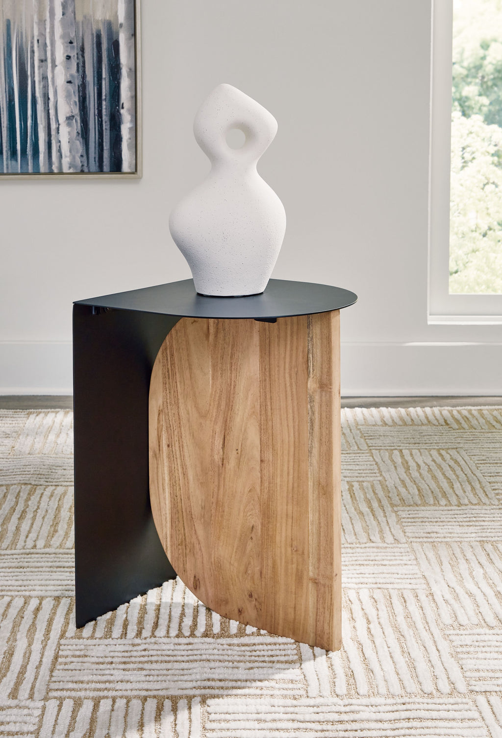 Black accent table with round top, natural wood base, styled with white vase