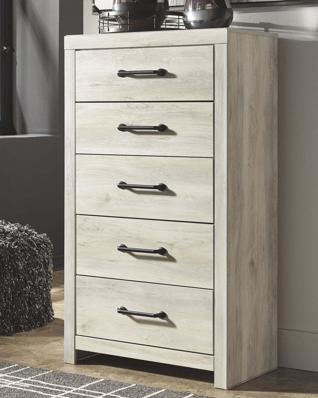 Side view of whitewash chest of drawers with five drawers and black bar pulls