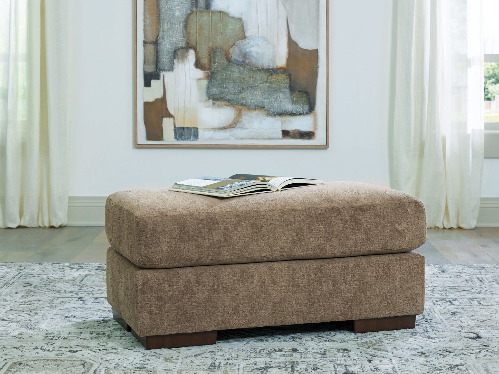 Square ottoman in light brown fabric with dark legs.