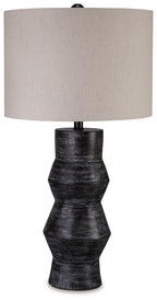 Distressed black table lamp with beige drum shade and ribbed pedestal base.