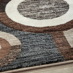 Close-up of geometric rug pattern with dark charcoal pile and ring motifs on cream