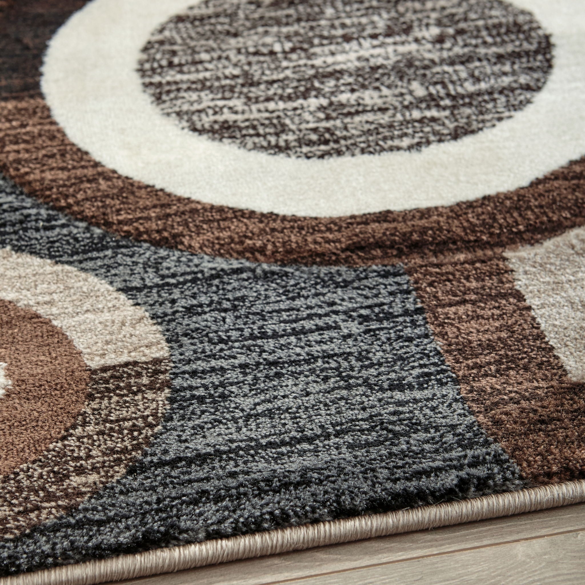 Close-up of geometric rug pattern with dark charcoal pile and ring motifs on cream