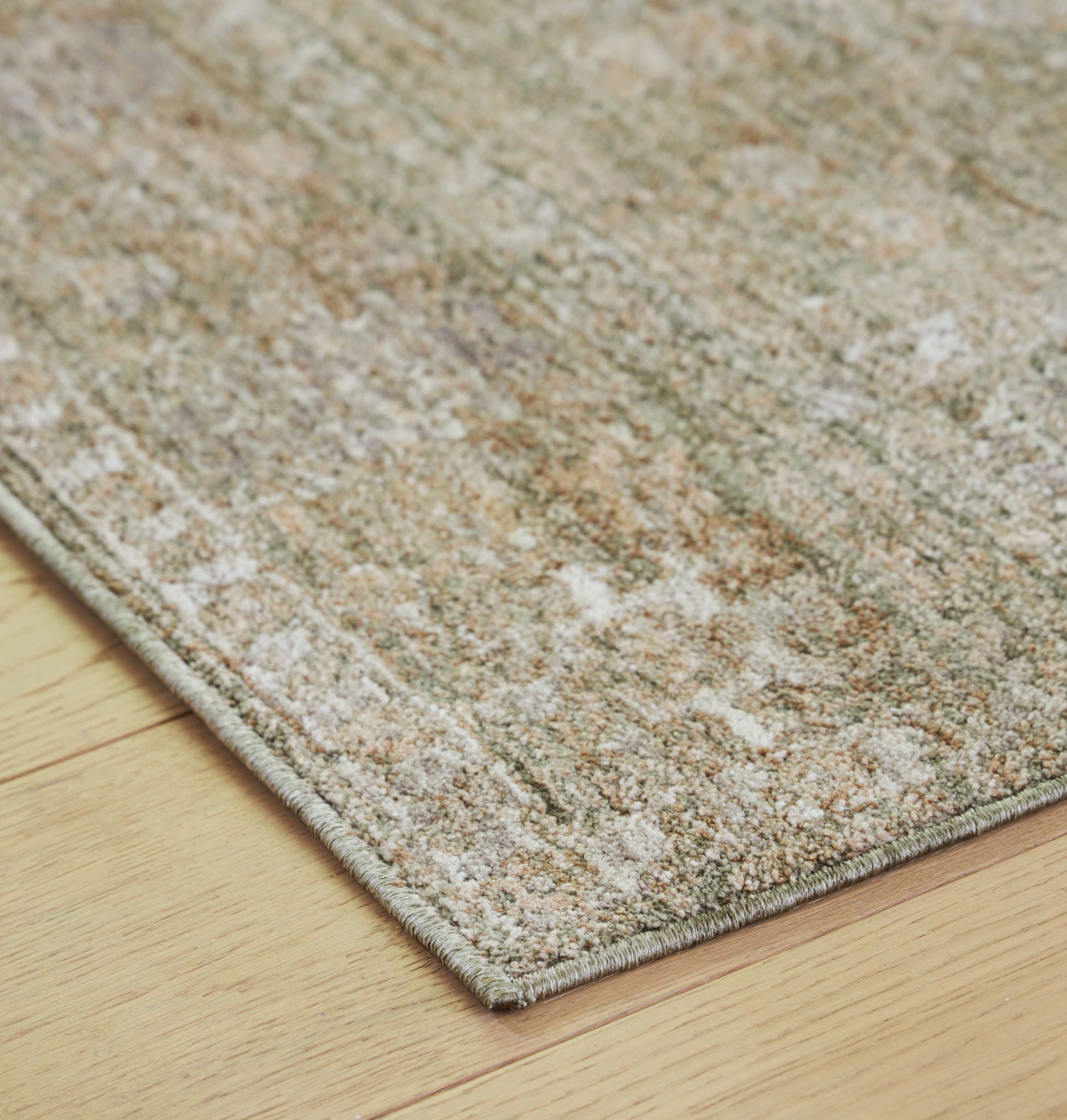 Corner view of light brown flatweave rug with distressed speckled fibers