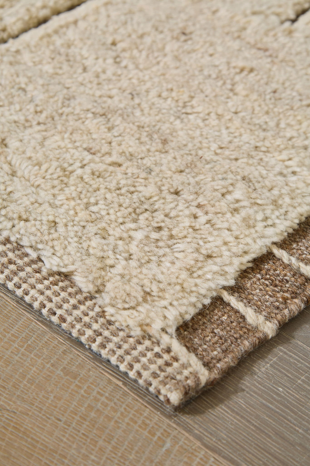 Beige rug corner with textured short pile and woven border