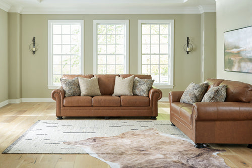 Brown fabric sofa and matching armchair with patterned throw pillows