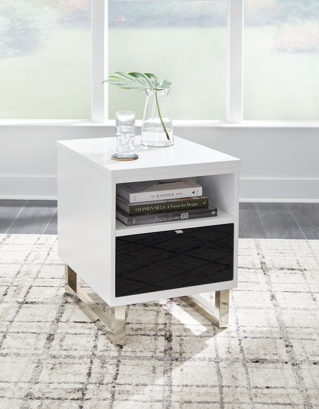 White chair side end table with open shelf, black drawer, and items on top