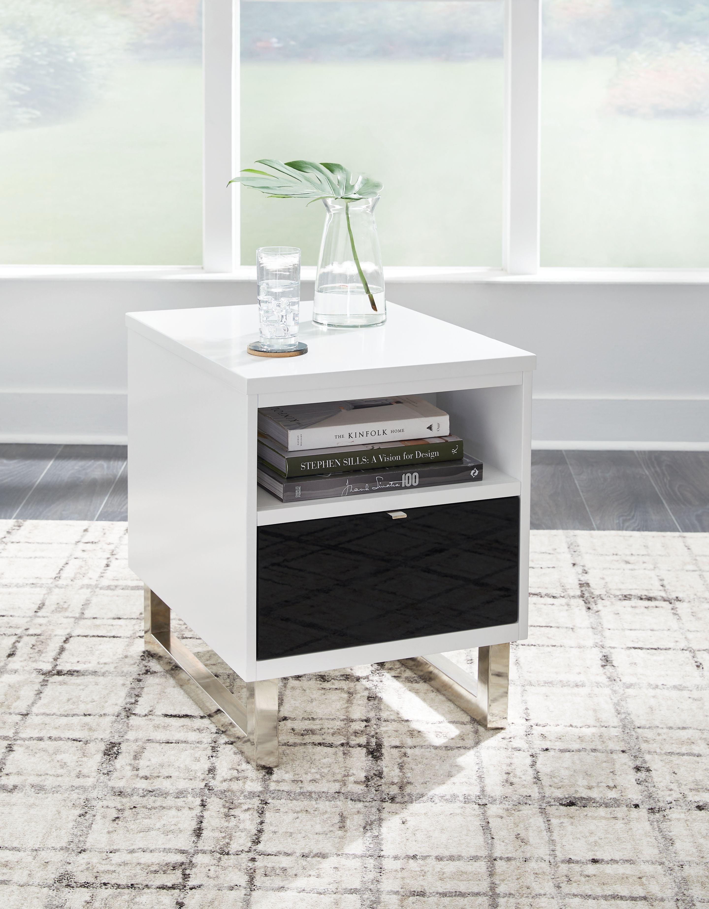 White chair side end table with open shelf, black drawer, and items on top