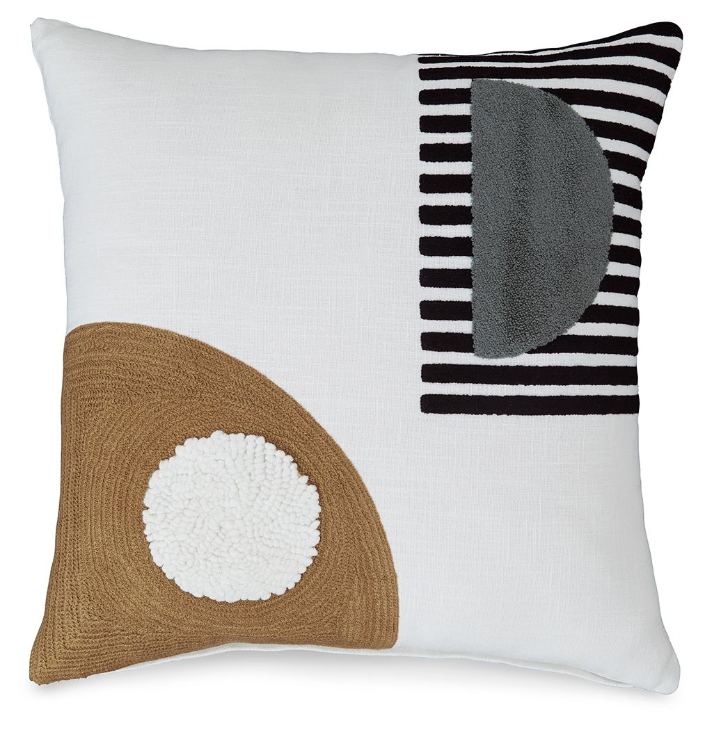 White pillow with brown triangle patch, white pom, and black-and-white striped corner