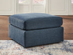 Blue accent ottoman with cushioned top and square base, dark feet.