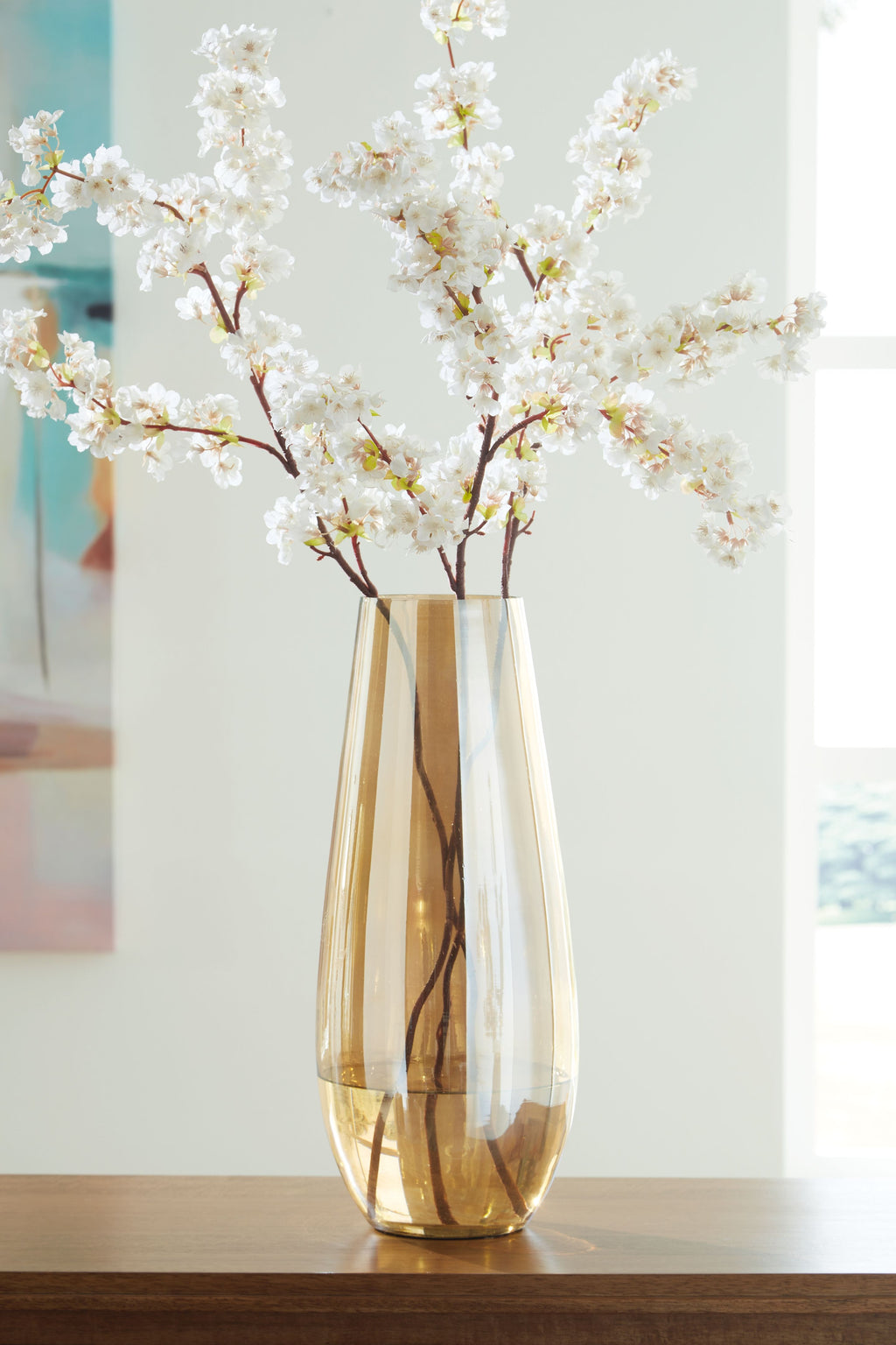 Amber glass vase with flared opening holding white blossoms