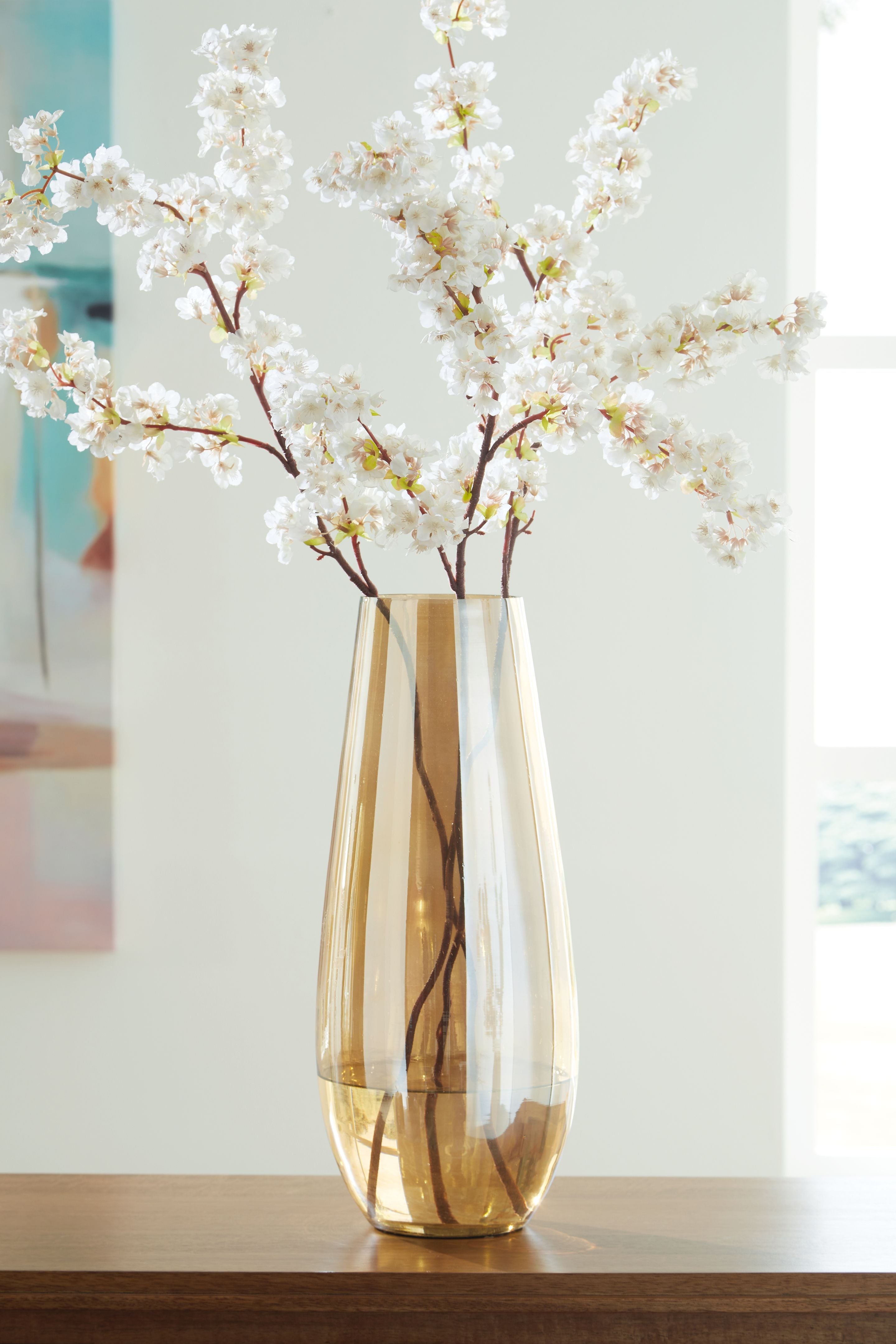 Amber glass vase with flared opening holding white blossoms