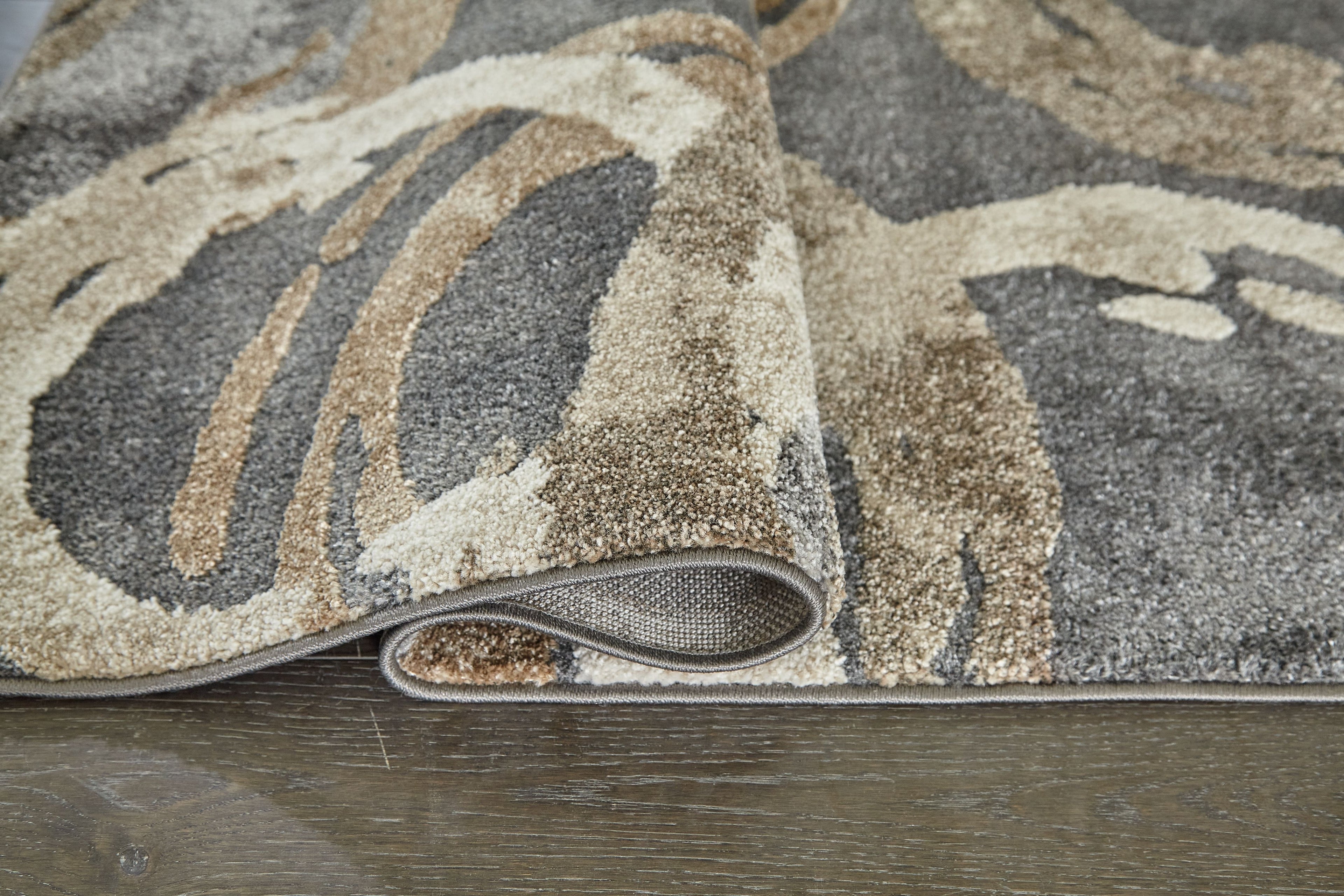 Faelyn rug edge with low pile and gray, cream, and tan abstract swirl design