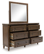 Brown wooden dresser with framed mirror and multiple drawers with metal pulls