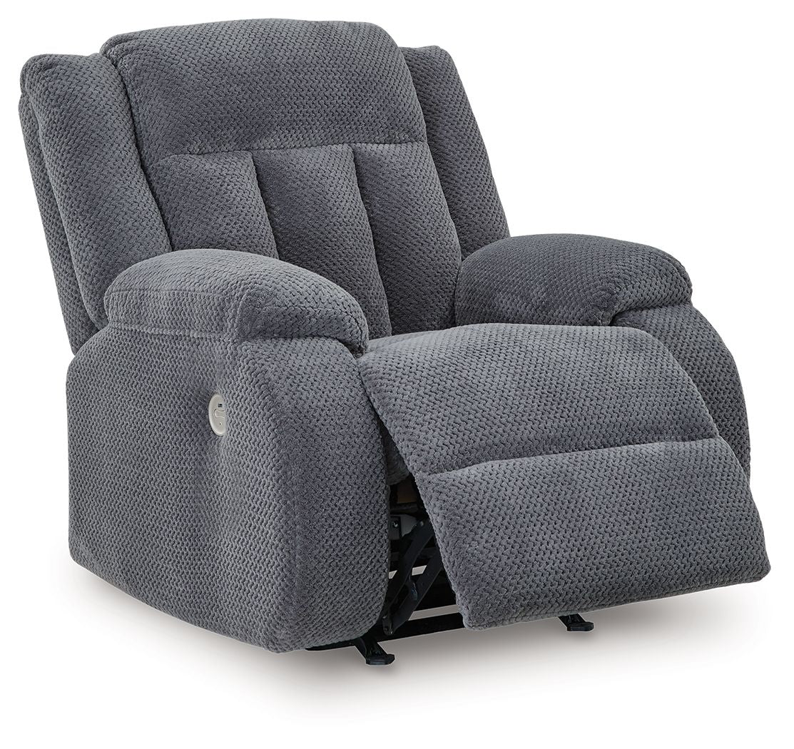 Fabric power rocker recliner in dark steel-gray, footrest raised, padded arms