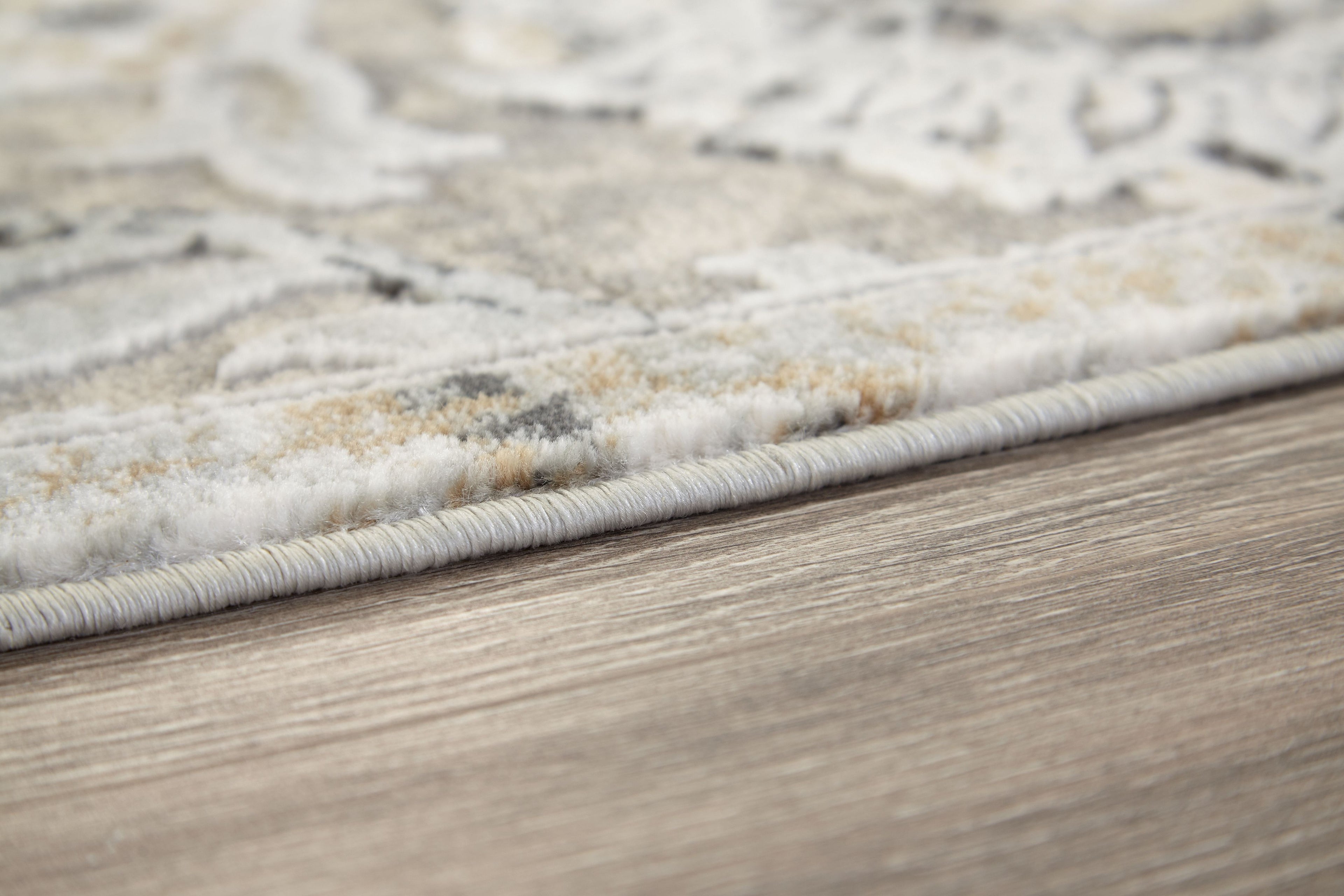 Gray and cream area rug edge with low pile and fringe-free border