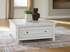 White coffee table with a long drawer and metal knobs on a paneled front.