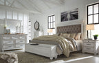 Upholstered panel bed in white with tufted taupe headboard and neatly styled bedding