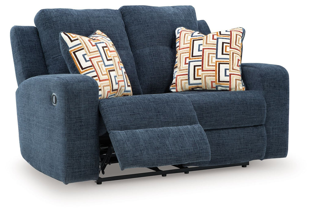 Blue reclining loveseat with two patterned throw pillows and visible footrest