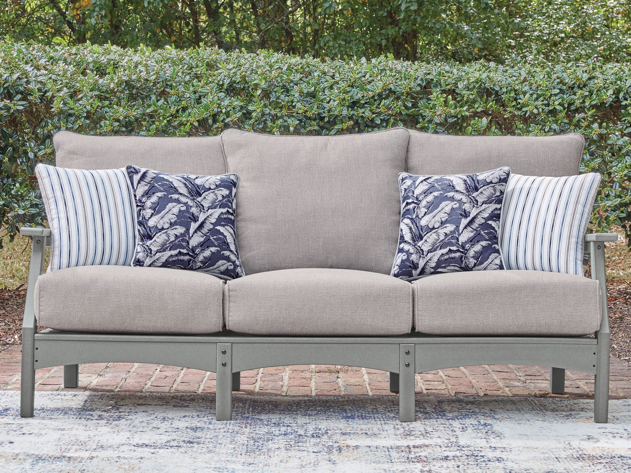Gray outdoor sofa with center back cushion and blue patterned throw pillows