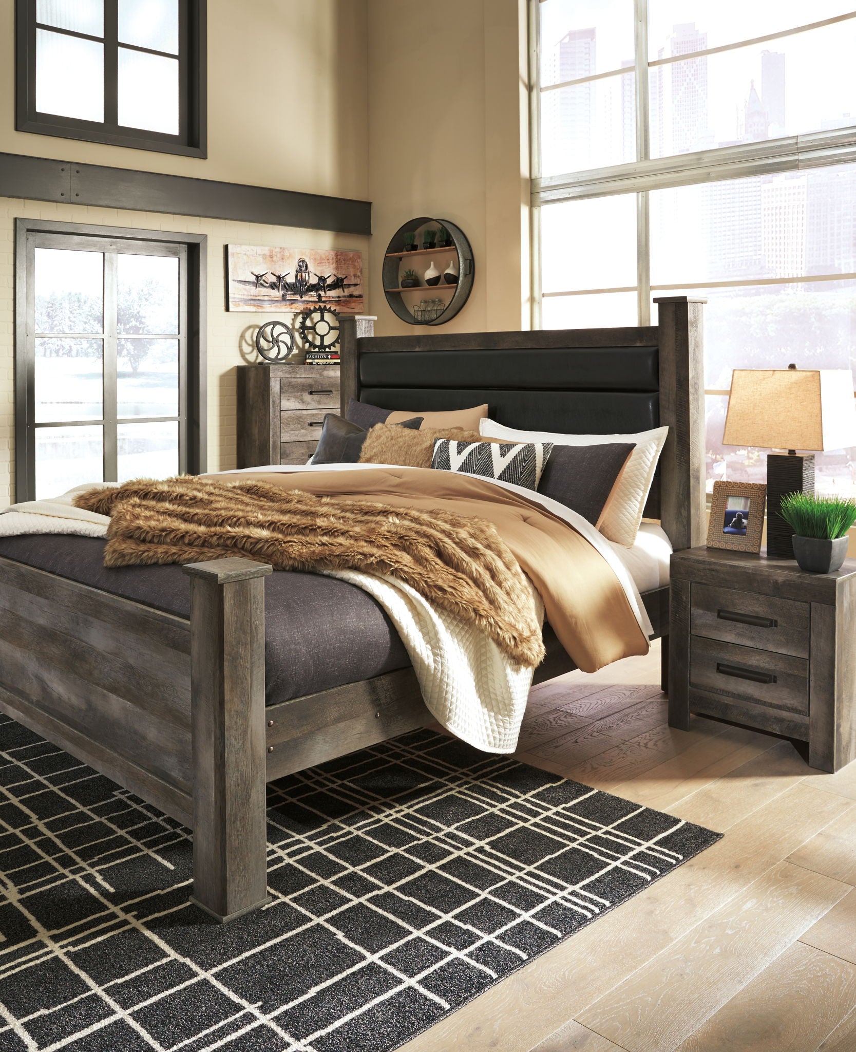 Gray poster bed with upholstered headboard and footboard, dressed with throw blanket