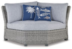 Light gray outdoor corner chair with blue fish and palm accent pillows