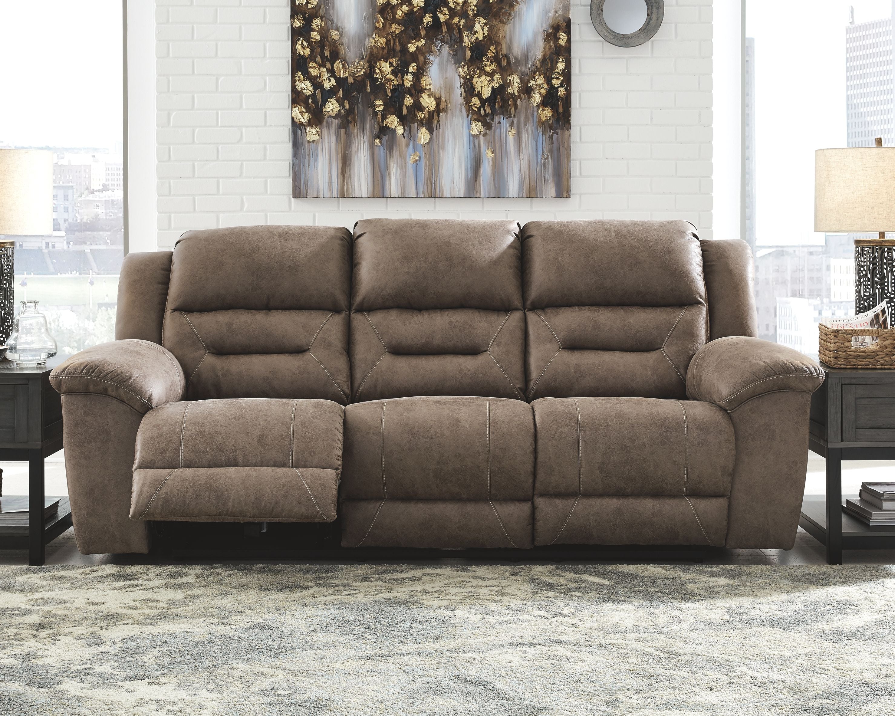Taupe-gray power reclining sofa with padded arms and tufted, segmented back design.