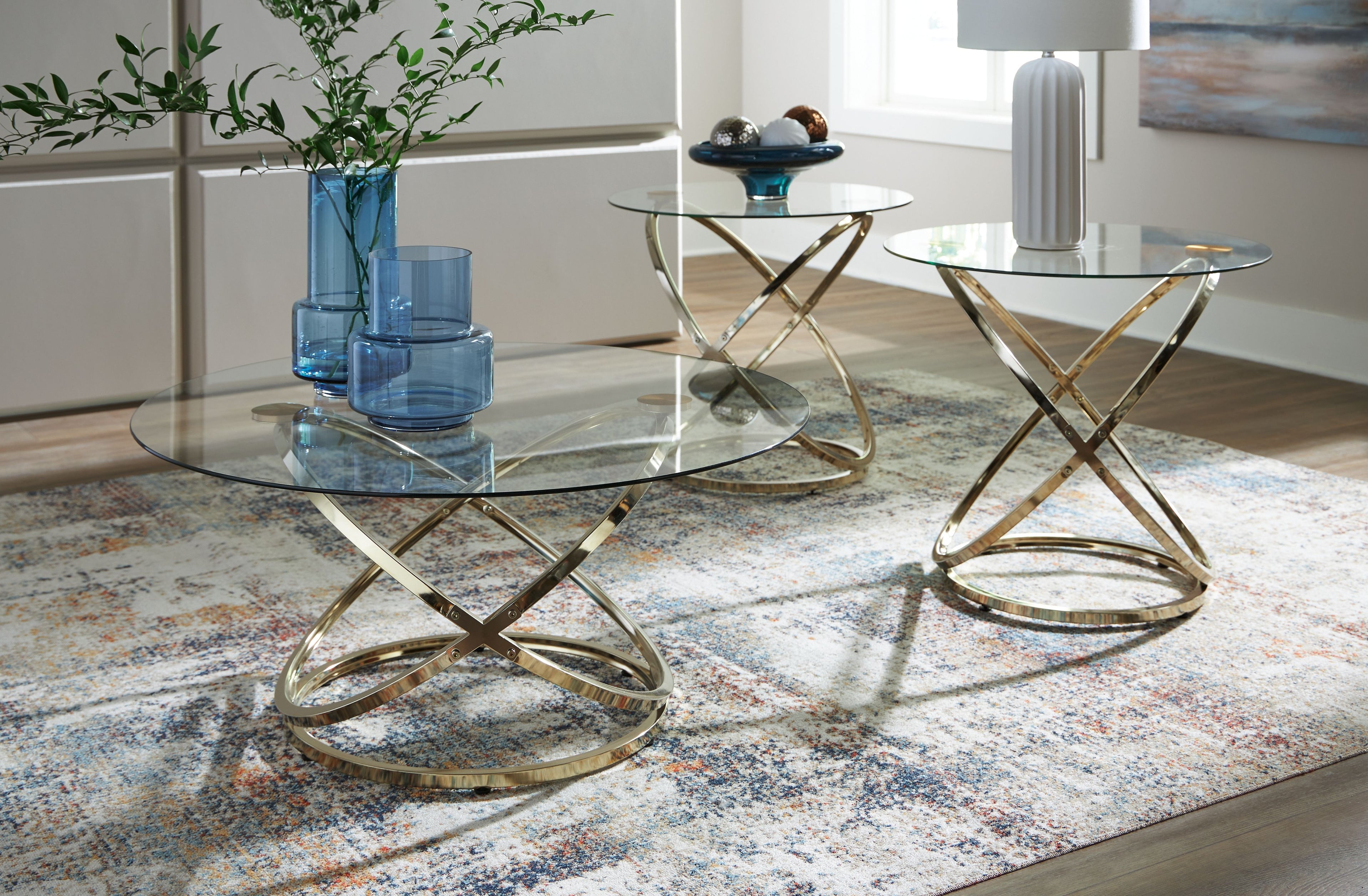 Round occasional tables set with clear glass tops and champagne crossed metal legs