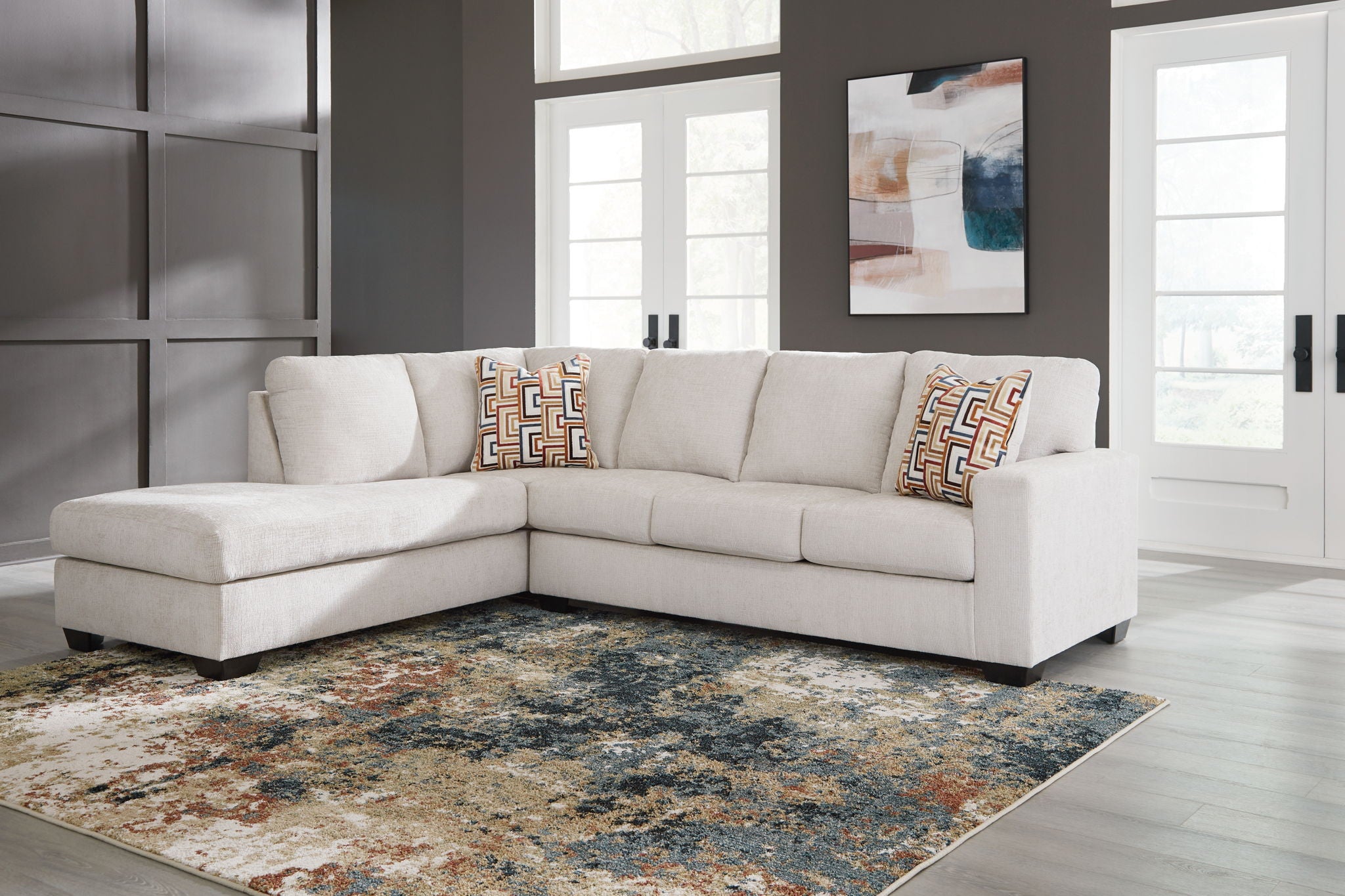 Light beige corner sectional sofa with patterned accent pillows and chaise section