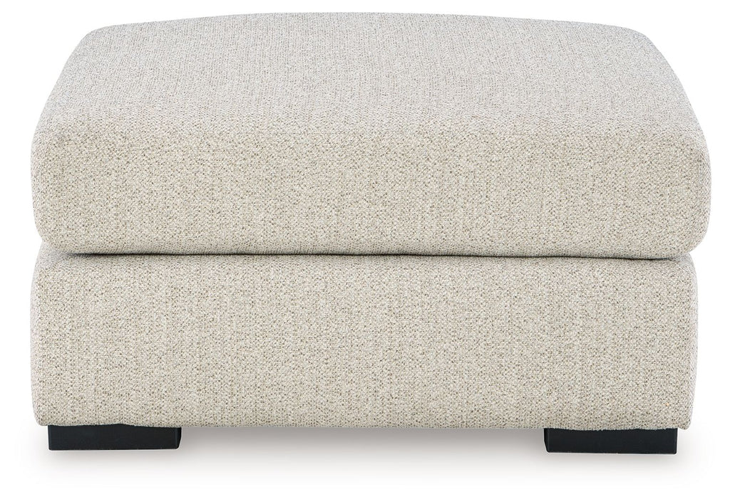 Oversized accent ottoman with rounded top cushion and dark block feet, pebble upholstery.