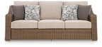 Beige sofa with woven wicker base, three cushions and two patterned back pillows