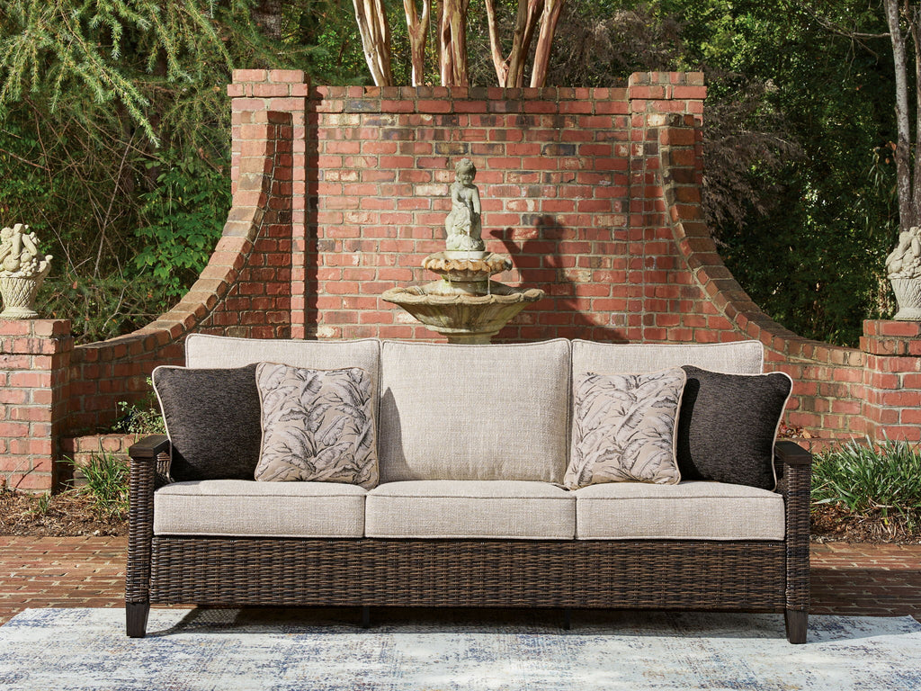 Dark brown wicker sofa with light gray cushions and patterned throw pillows