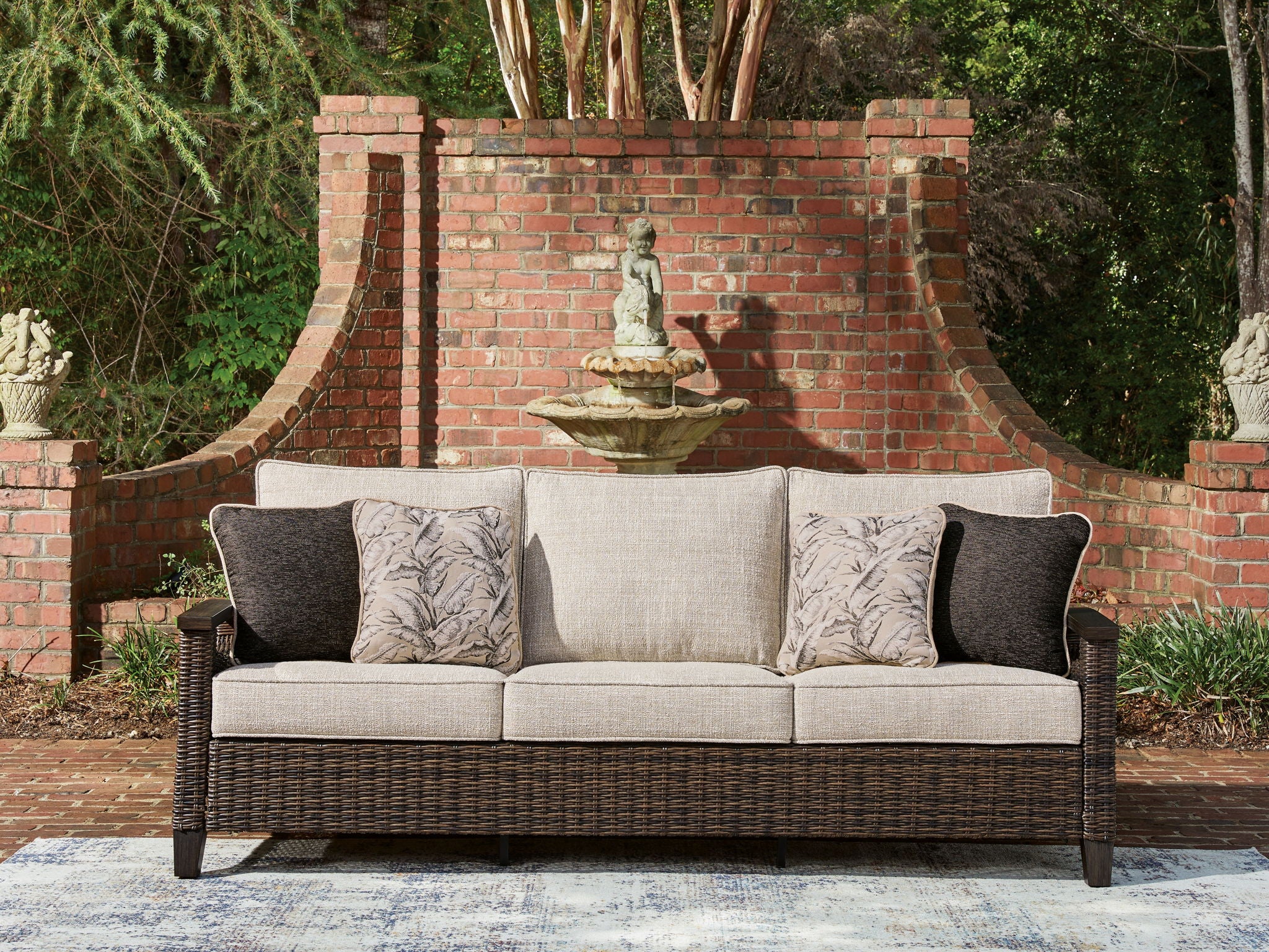 Dark brown wicker sofa with light gray cushions and patterned throw pillows