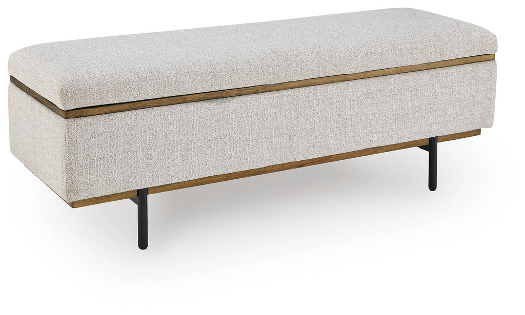 Stone upholstered storage bench with gold trim and dark tapered legs, hinged lid