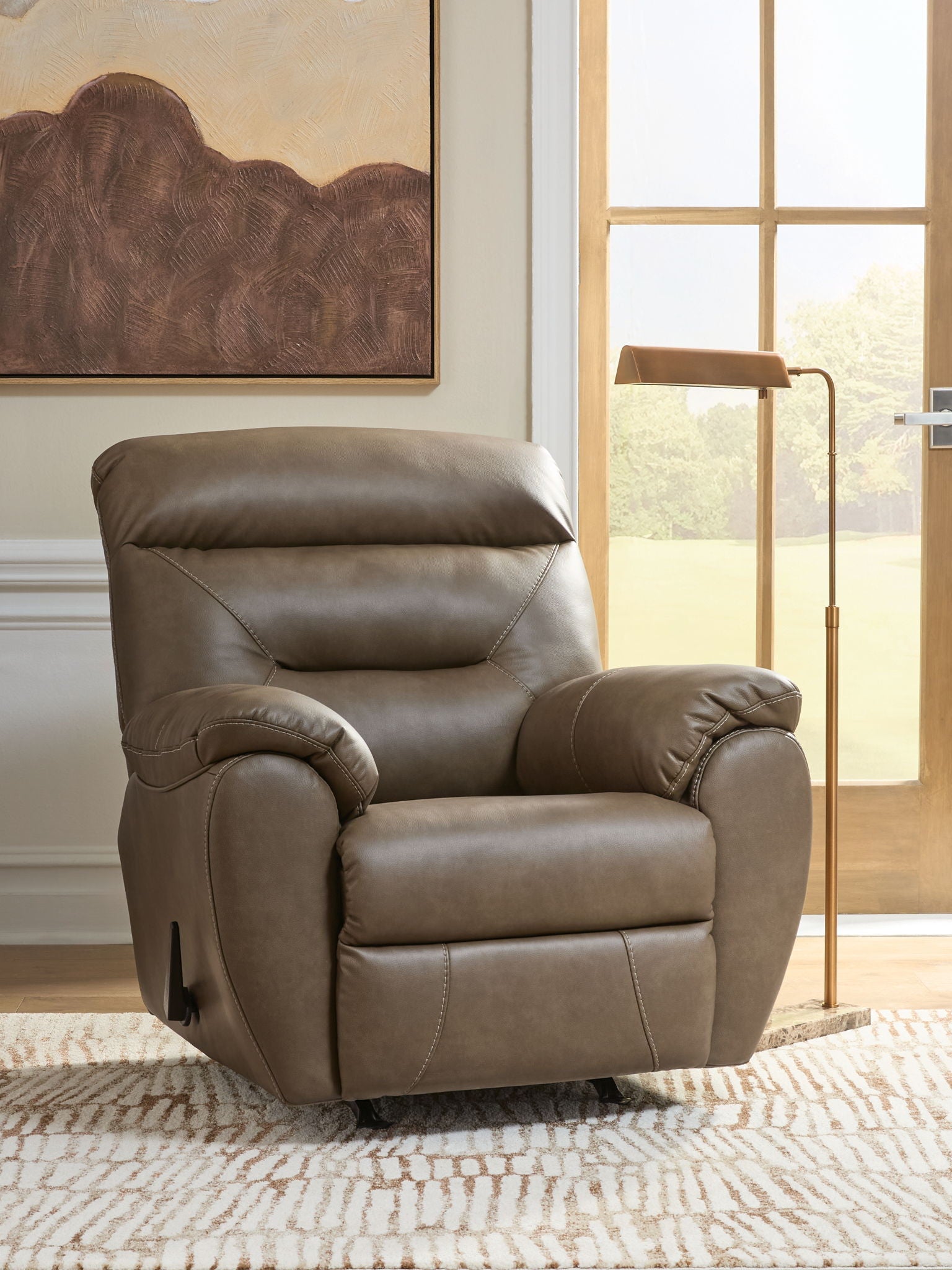 Dark gray rocker recliner with reclining backrest, padded arms, and seam stitching