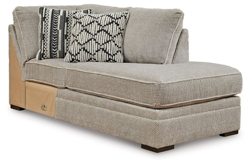 Corner chaise lounge with light gray upholstery, two patterned accent pillows, corner arm
