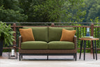 Outdoor loveseat with green cushions, brown woven wicker frame, and two brown accent pillows