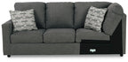 Dark gray wedge sofa with three seat cushions and two patterned throw pillows