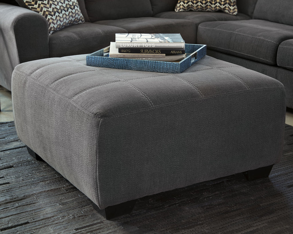 Slate gray ottoman seat with tufted stitching and visible dark legs